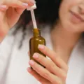 Wanita mengoleskan serum wajah untuk merawat kulit dengan manfaat retinol untuk wajah
