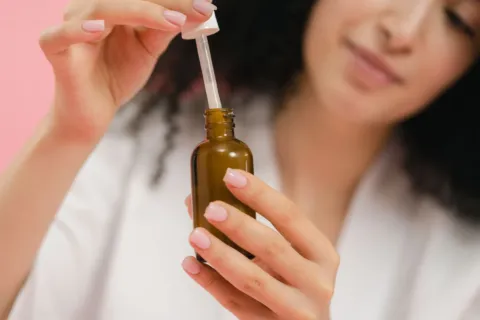 Wanita mengoleskan serum wajah untuk merawat kulit dengan manfaat retinol untuk wajah