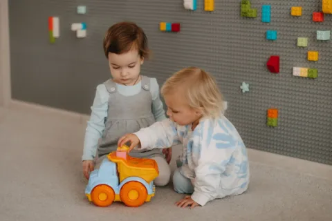Dua anak balita sedang bermain balok susun bersama sebagai bentuk cara mengajarkan anak berbagi mainan
