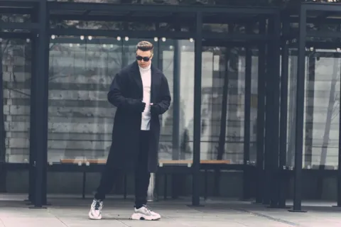 Gaya berpakaian musim dingin dengan long coat krem dan syal rajut yang stylish