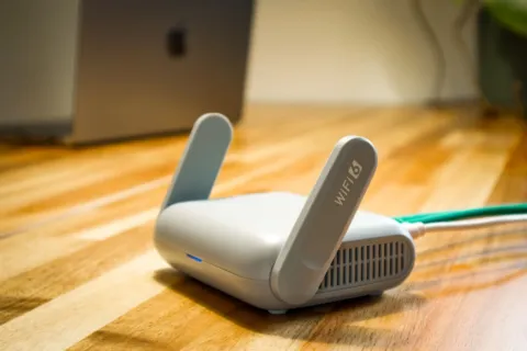 Perangkat router Mesh Wi-Fi putih terpasang rapi di atas meja ruang keluarga rumah luas