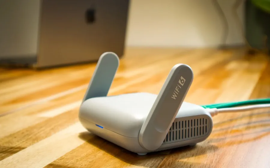 Perangkat router Mesh Wi-Fi putih terpasang rapi di atas meja ruang keluarga rumah luas