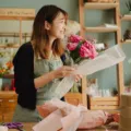 Seseorang sedang merangkai buket bunga segar di studio usaha florist rumahan