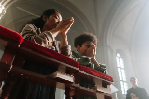 Momen ibu membimbing anak balita berdoa bersama di meja makan dengan hangat