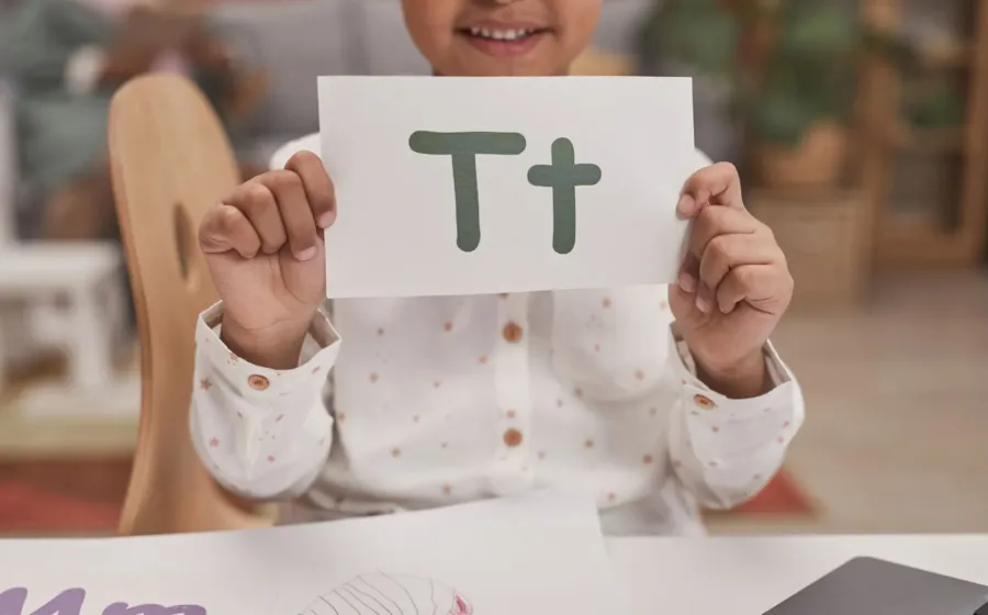 Anak balita sedang bermain magnet huruf di pintu rumah untuk belajar mengenal abjad secara menyenangkan