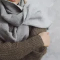 Gaya berpakaian saat cuaca dingin dengan teknik layering sweter rajut dan mantel panjang yang rapi