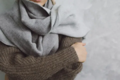 Gaya berpakaian saat cuaca dingin dengan teknik layering sweter rajut dan mantel panjang yang rapi