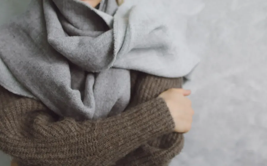 Gaya berpakaian saat cuaca dingin dengan teknik layering sweter rajut dan mantel panjang yang rapi