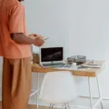 Seseorang menerapkan kebiasaan menjaga postur tubuh yang baik saat duduk di meja kerja depan laptop