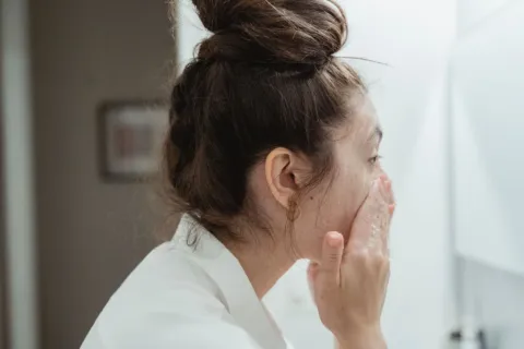 Seseorang sedang membasuh wajah dengan air mengalir untuk mendapatkan manfaat cuci muka yang benar
