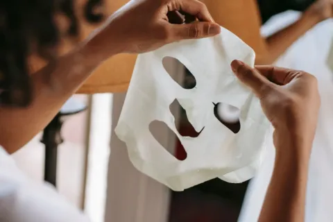 Seorang wanita menikmati manfaat sheet mask rutin untuk melembapkan kulit wajah
