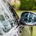 Seseorang sedang mengelap kaca spion mobil dengan kain mikrofiber halus