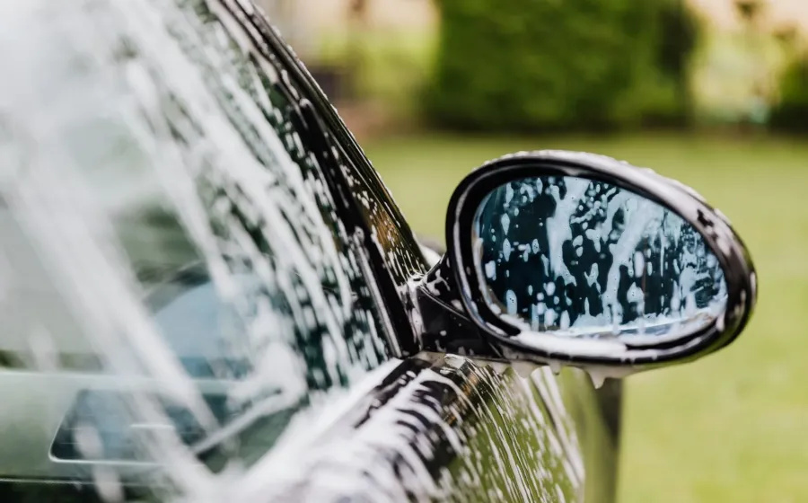 Seseorang sedang mengelap kaca spion mobil dengan kain mikrofiber halus