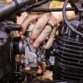 Perawatan karburator motor klasik menggunakan obeng untuk membersihkan mangkok karburator