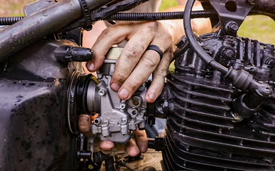 Perawatan karburator motor klasik menggunakan obeng untuk membersihkan mangkok karburator