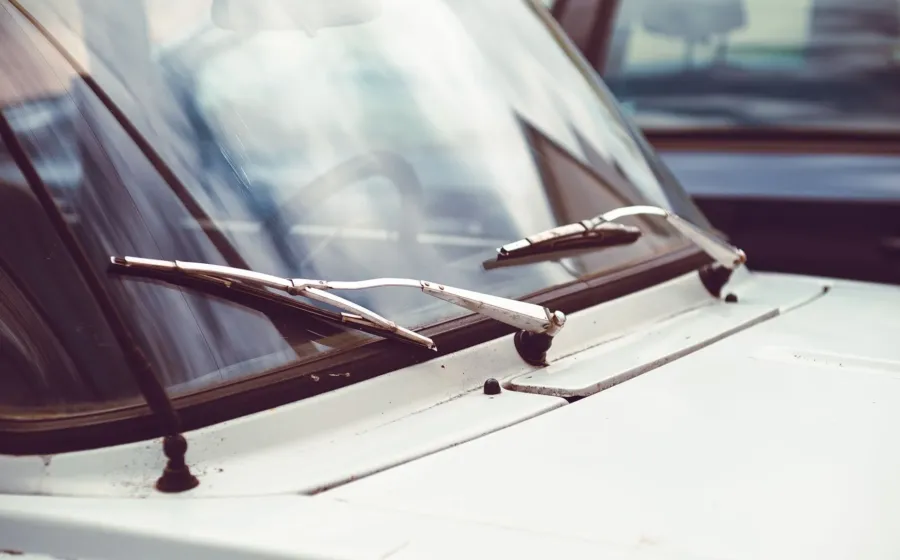 Pemilik mobil sedang membersihkan karet wiper mobil memakai kain mikrofiber basah