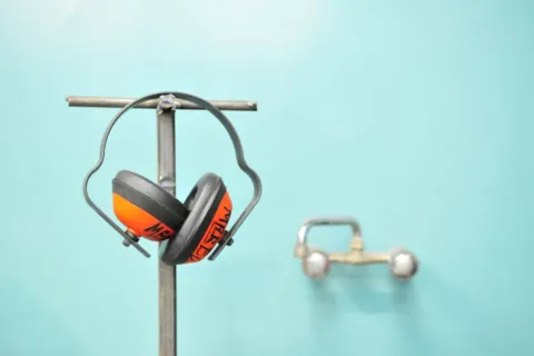 Seseorang sedang memakai rekomendasi headphone peredam bising saat bekerja fokus di depan laptop