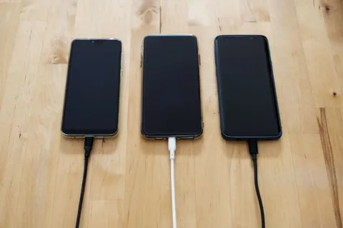 Kabel data awet nilon rajut warna hitam terhubung ke smartphone di atas meja kerja