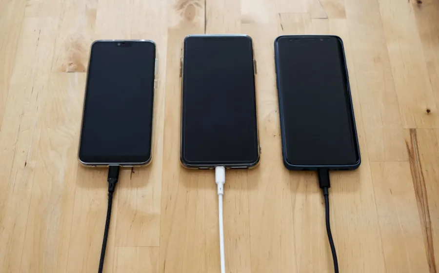 Kabel data awet nilon rajut warna hitam terhubung ke smartphone di atas meja kerja