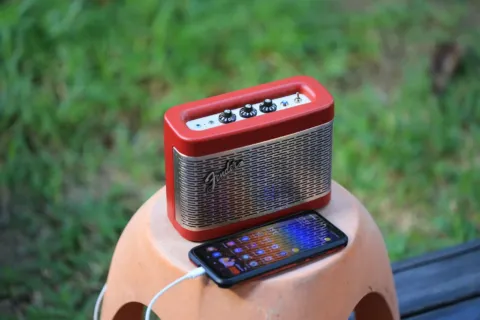 Rekomendasi speaker portable outdoor tahan air diletakkan di atas batu dekat area kemping