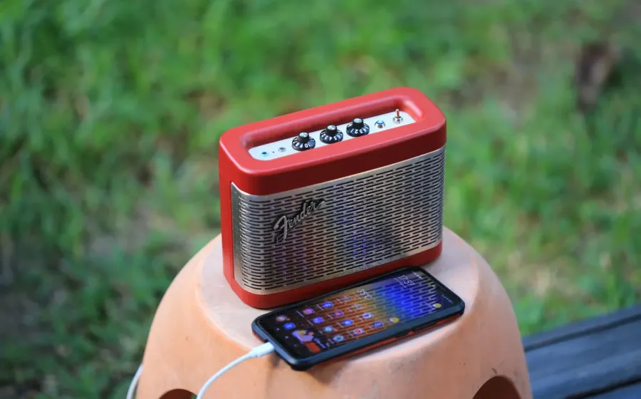 Rekomendasi speaker portable outdoor tahan air diletakkan di atas batu dekat area kemping